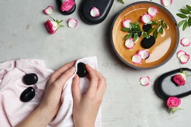 Photo of Woman with spa stones at grey table, top view