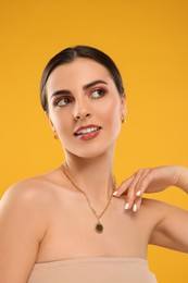 Photo of Beautiful woman with elegant jewelry on orange background