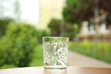 Photo of Glass of fresh water on wooden table outdoors