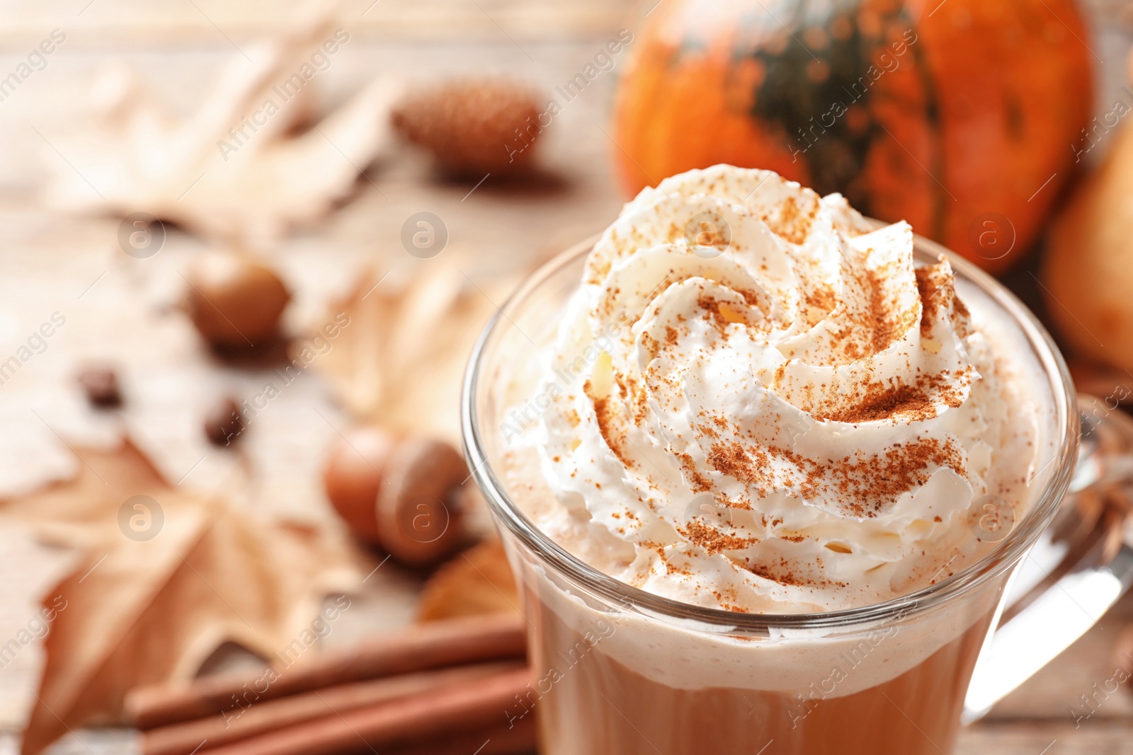 Photo of Glass cup with tasty pumpkin spice latte on wooden table, closeup