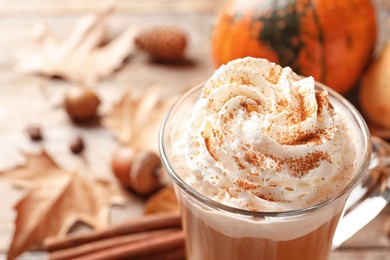 Glass cup with tasty pumpkin spice latte on wooden table, closeup