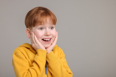 Photo of Portrait of surprised little boy on grey background, space for text