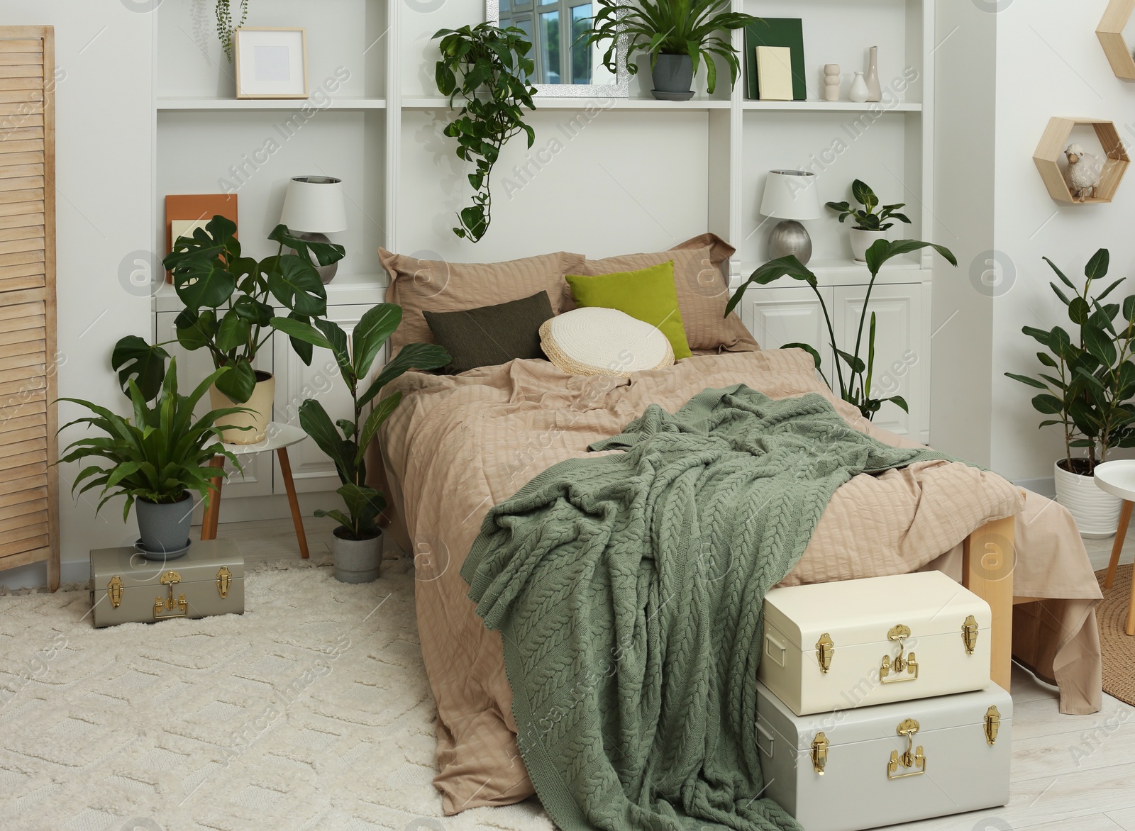 Photo of Stylish bedroom with comfortable bed and different houseplants. Interior design