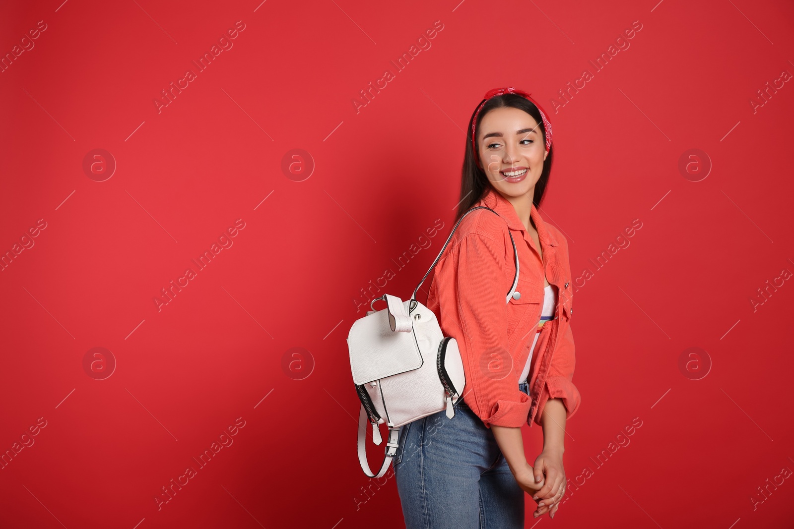 Photo of Beautiful young woman with stylish leather backpack on red background. Space for text