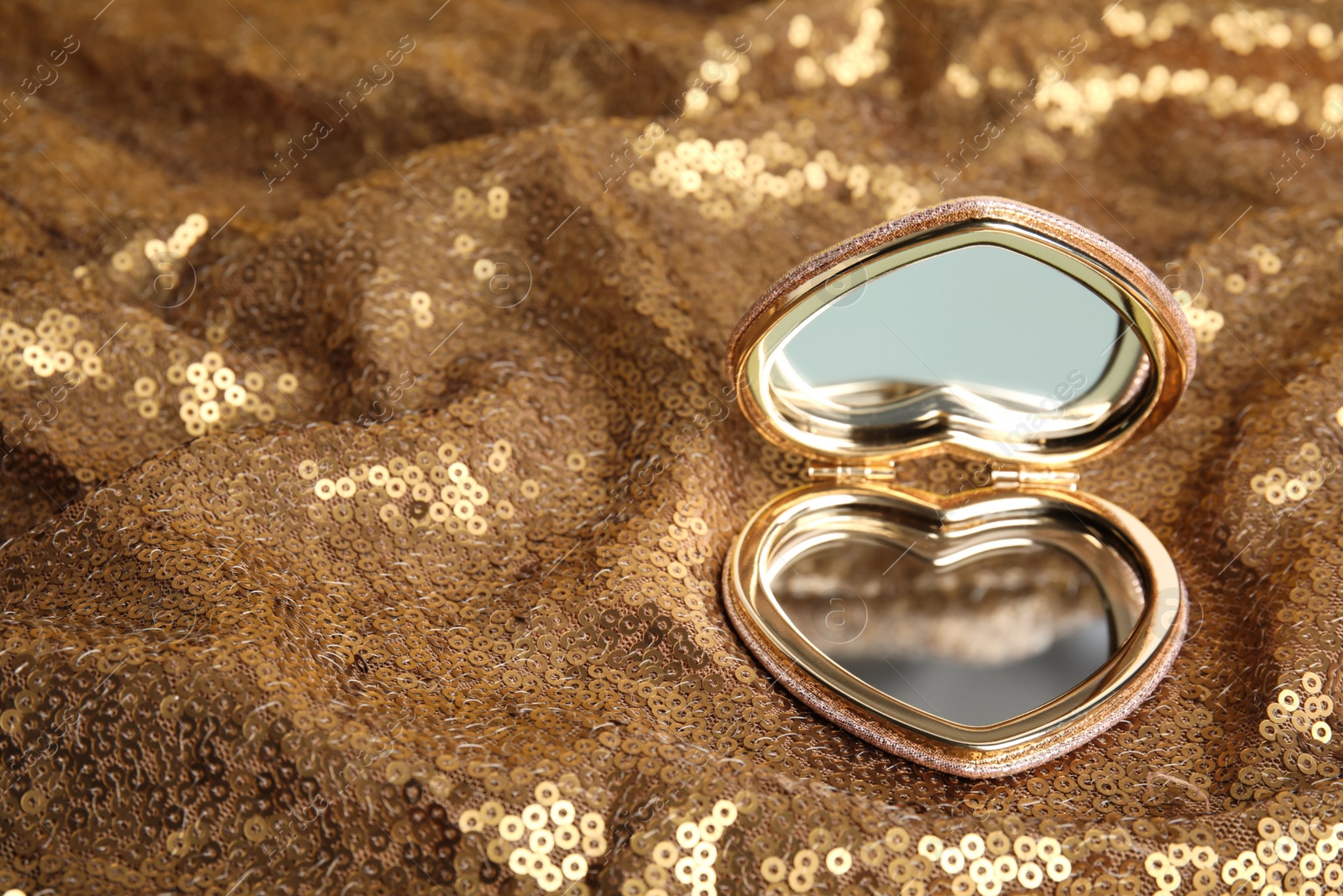 Photo of Stylish heart shaped cosmetic pocket mirror on gold fabric, space for text