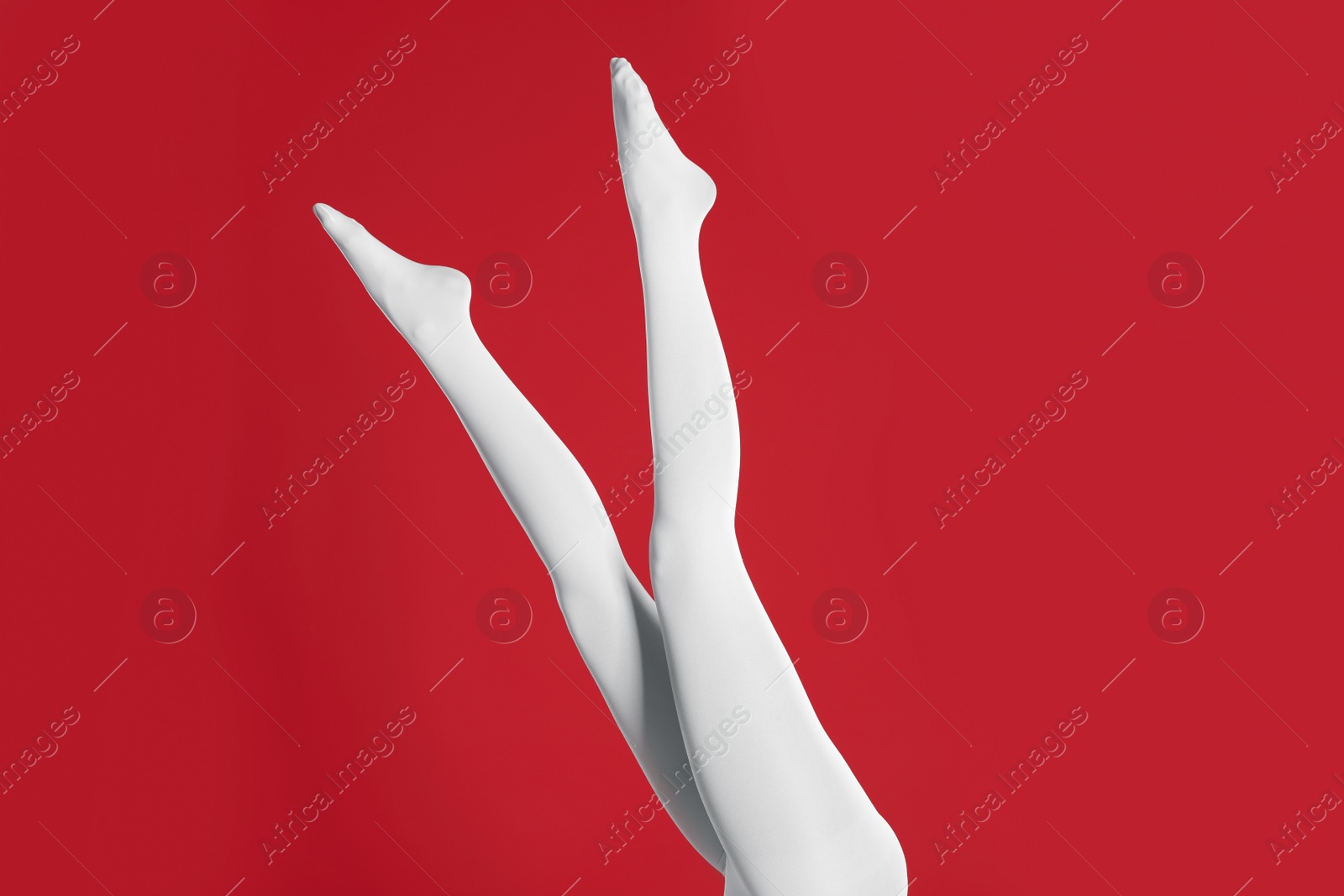 Photo of Woman wearing white tights on red background, closeup of legs