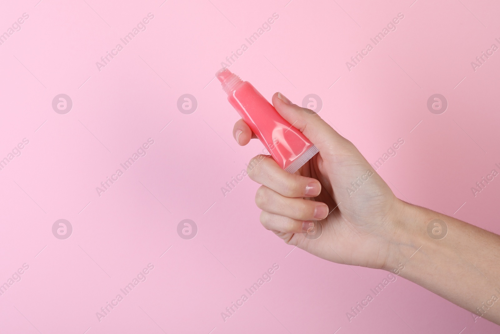 Photo of Woman with lip balm on pink background, closeup