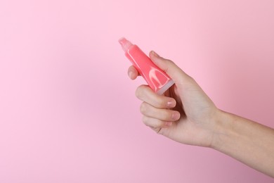 Photo of Woman with lip balm on pink background, closeup