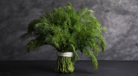 Photo of Bunch of fresh green dill on black table