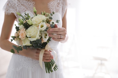 Photo of Young bride with beautiful wedding bouquet in room, closeup. Space for text