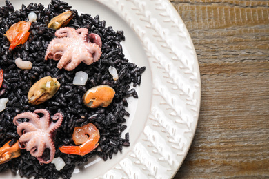 Delicious black risotto with seafood served on plate, top view