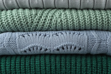 Photo of Stack of warm clothes as background, closeup. Autumn season