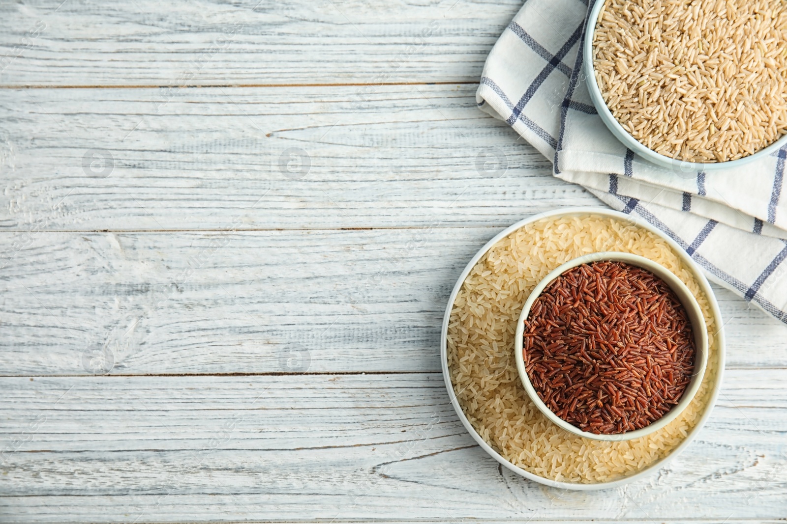 Photo of Flat lay composition with different types of rice and space for text on wooden table