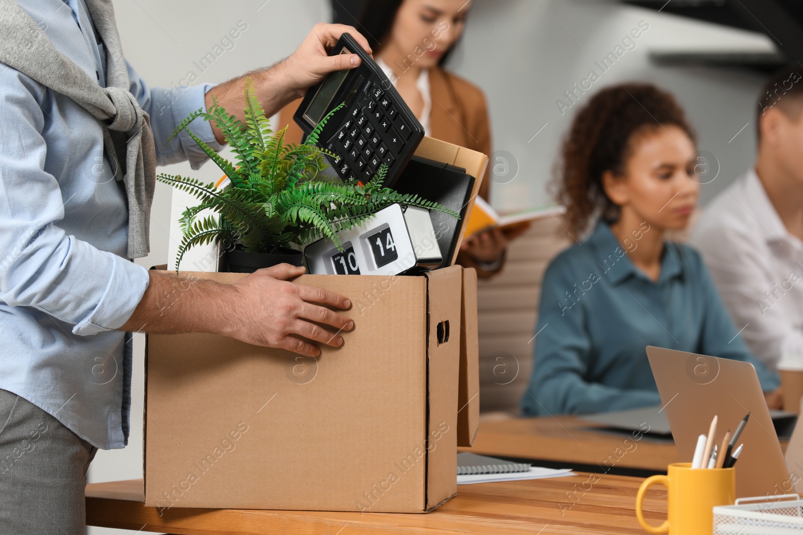 Photo of Young dismissed man packing stuff into box at office, closeup. Space for text