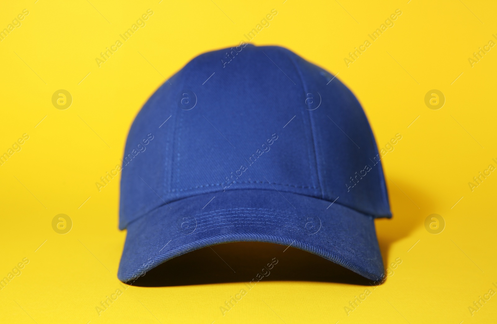 Photo of Stylish blue baseball cap on yellow background