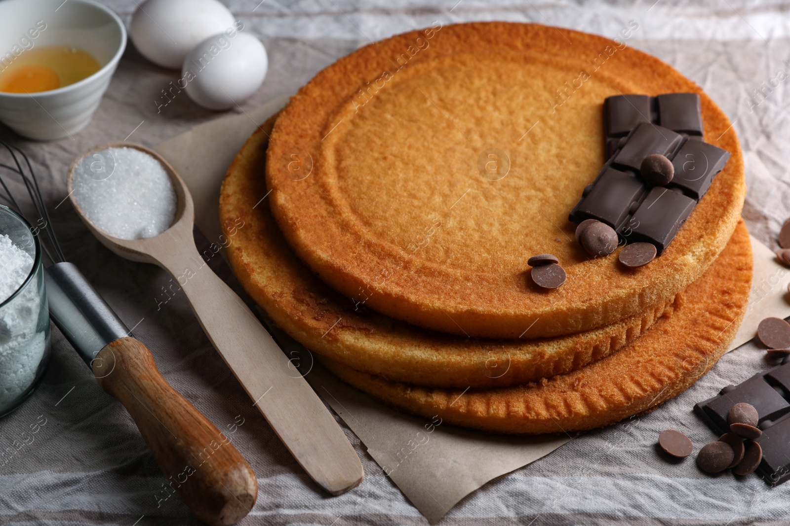 Photo of Delicious homemade sponge cakes and ingredients on grey tablecloth, closeup