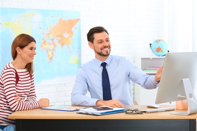 Photo of Male manager consulting client in travel agency