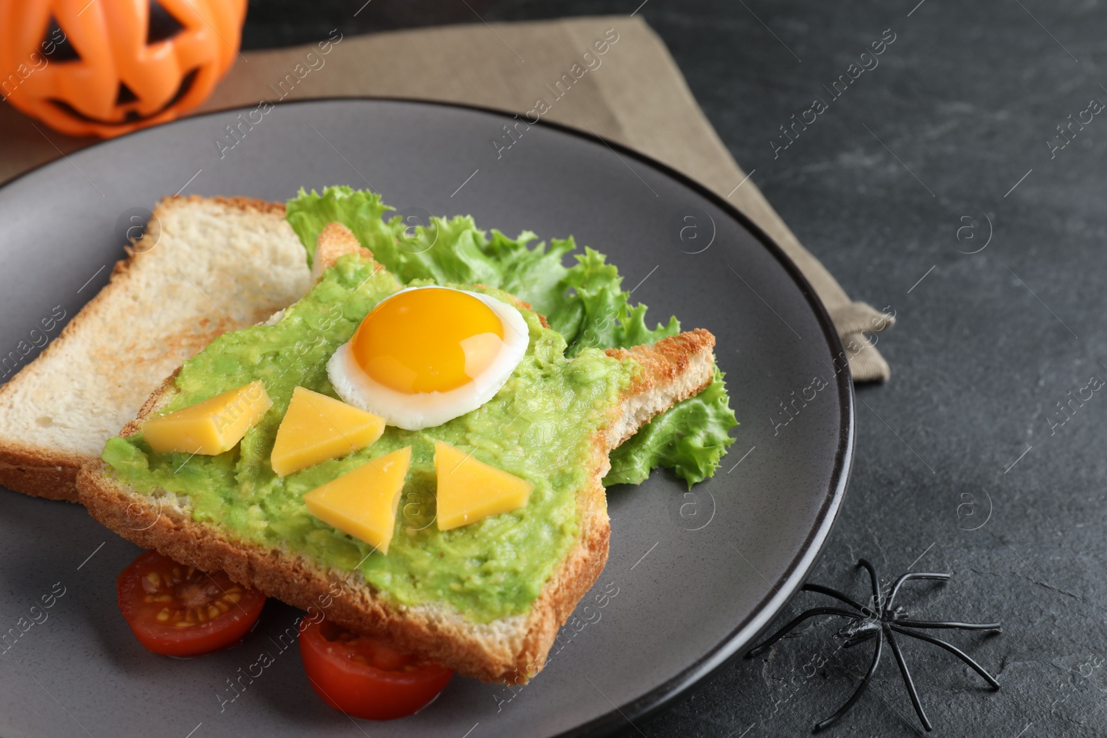 Photo of Halloween themed breakfast served on black table, closeup. Tasty sandwich with fried egg