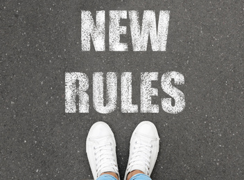 Image of Woman standing near text NEW RULES on asphalt, top view