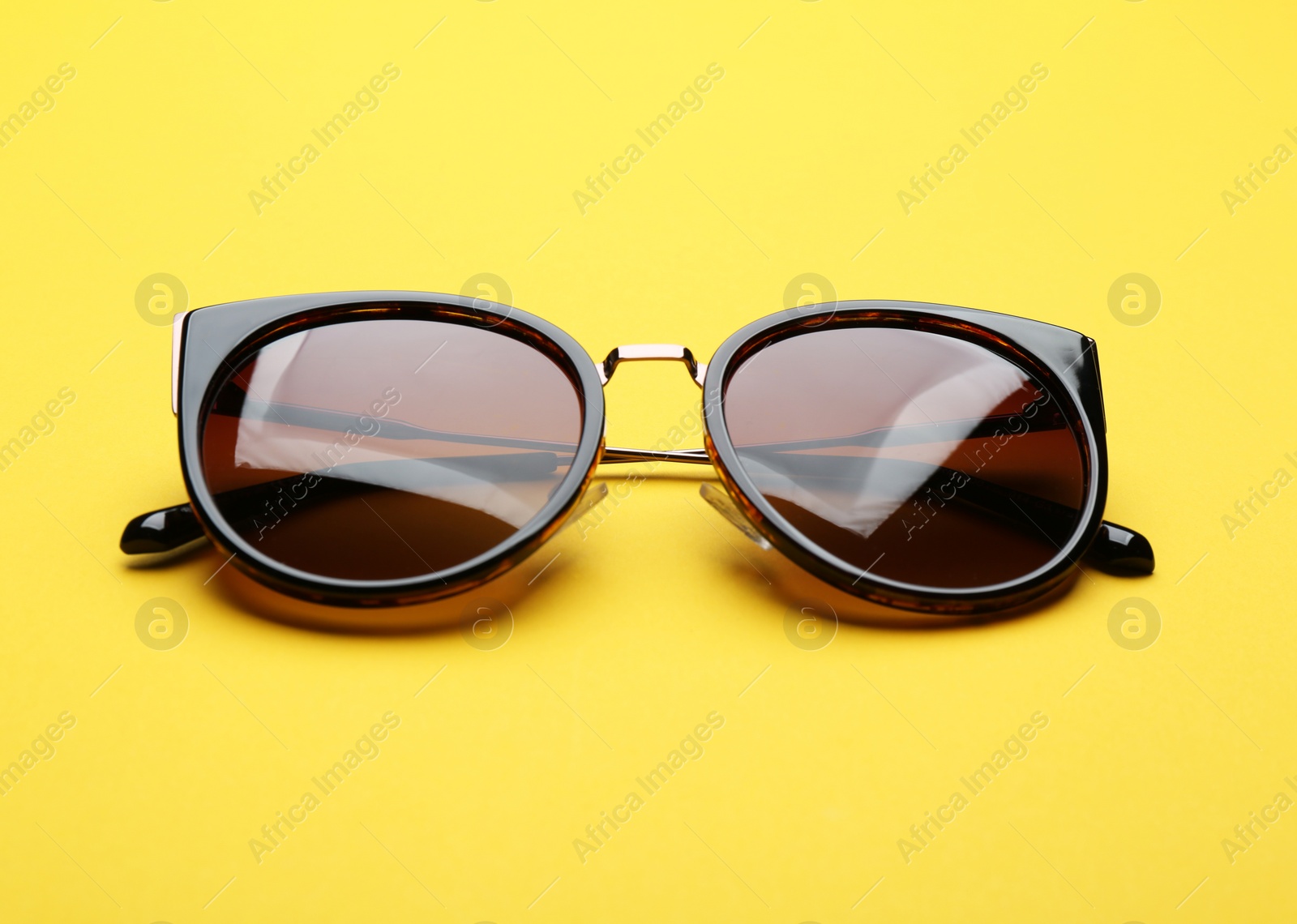 Photo of Stylish sunglasses on yellow background. Fashionable accessory