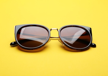 Stylish sunglasses on yellow background. Fashionable accessory