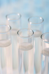 Photo of Laboratory analysis. Many glass test tubes on light blue background, closeup