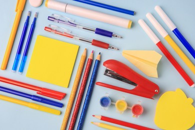 Flat lay composition with sticky note and other school stationery on light blue background, space for text. Back to school