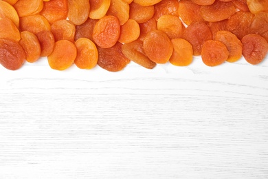 Dried apricots on white wooden table, top view with space for text. Healthy fruit