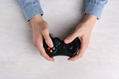 Man using wireless game controller at white table, top view