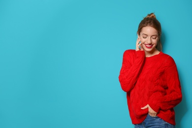 Photo of Beautiful young woman in warm sweater on color background. Space for text