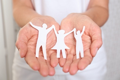 Photo of Young woman holding paper family figure, closeup of hands