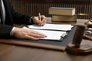 Photo of Lawyer working with documents at wooden table indoors, closeup