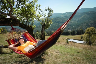 Photo of Young woman resting in hammock outdoors on sunny day