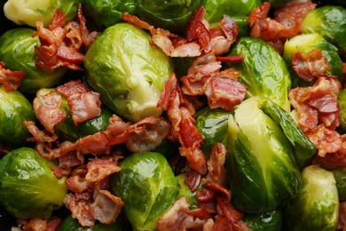 Tasty cooked Brussels sprouts with bacon as background, top view