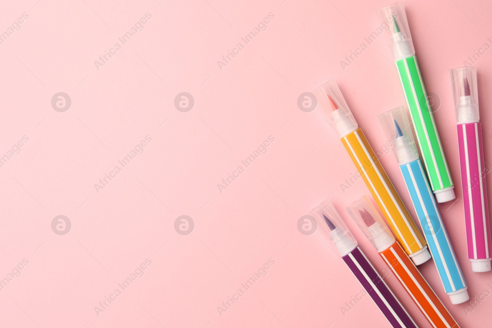 Photo of Many bright markers on pink background, flat lay. Space for text
