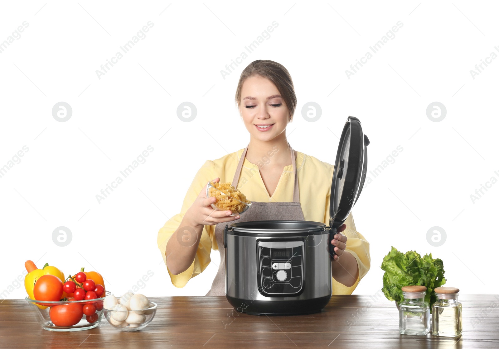 Photo of Young woman preparing food with modern multi cooker at table against white background