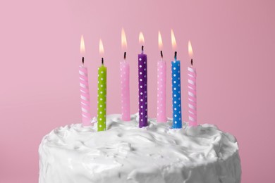 Photo of Delicious cake with cream and burning candles on pink background, closeup