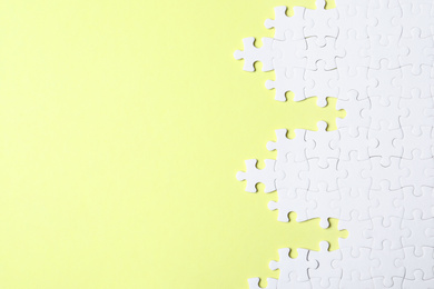 Photo of Blank white puzzle pieces on yellow background, flat lay. Space for text