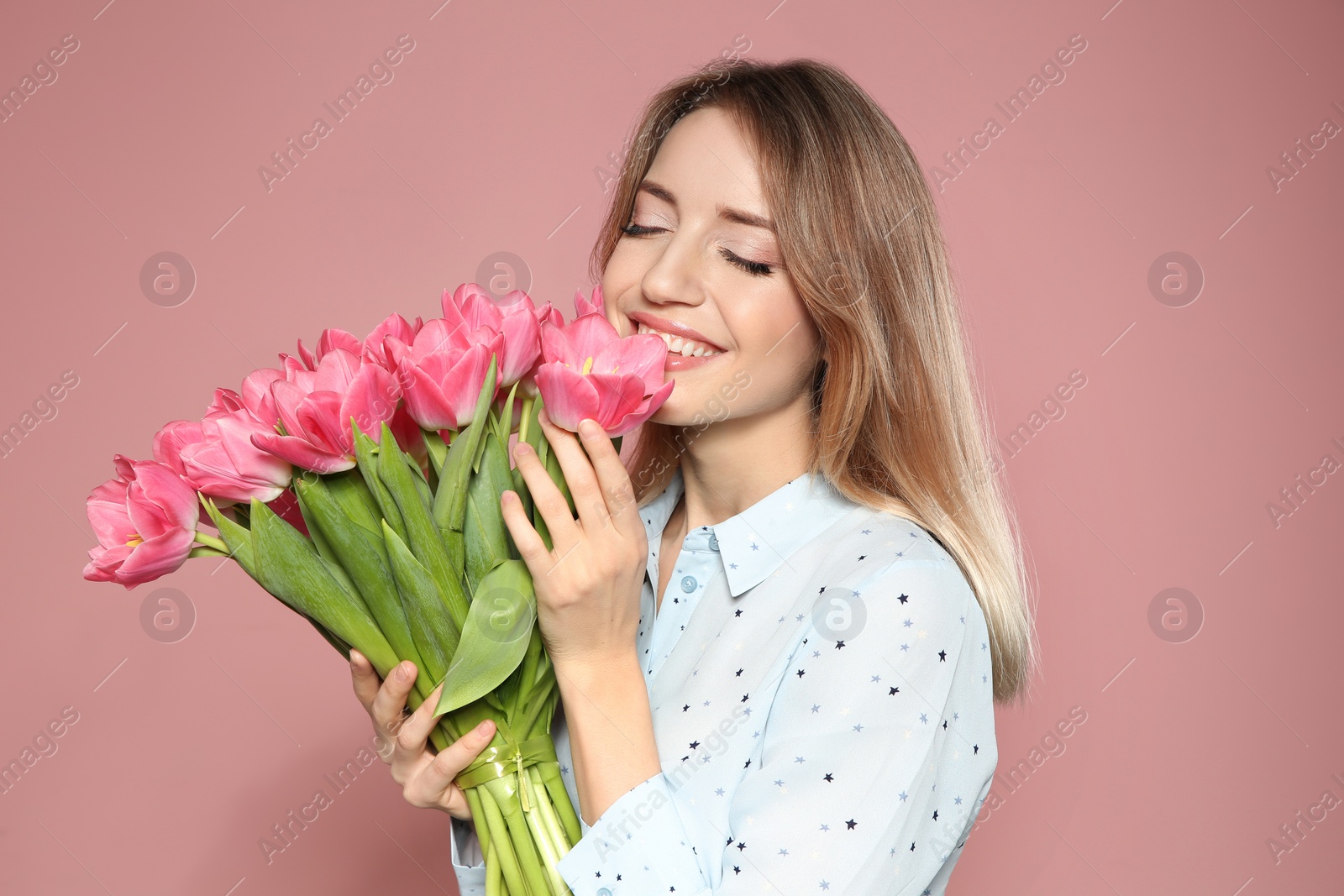 Photo of Portrait of beautiful smiling girl with spring tulips on pink background. International Women's Day