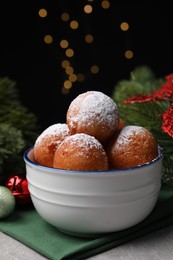 Photo of Delicious sweet buns in bowl and decor on table against black background with blurred lights