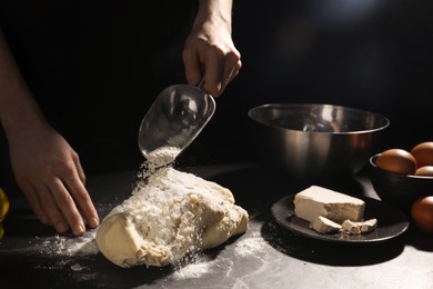 Photo of Preparing bread. Woman making dough at black table on dark background, closeup