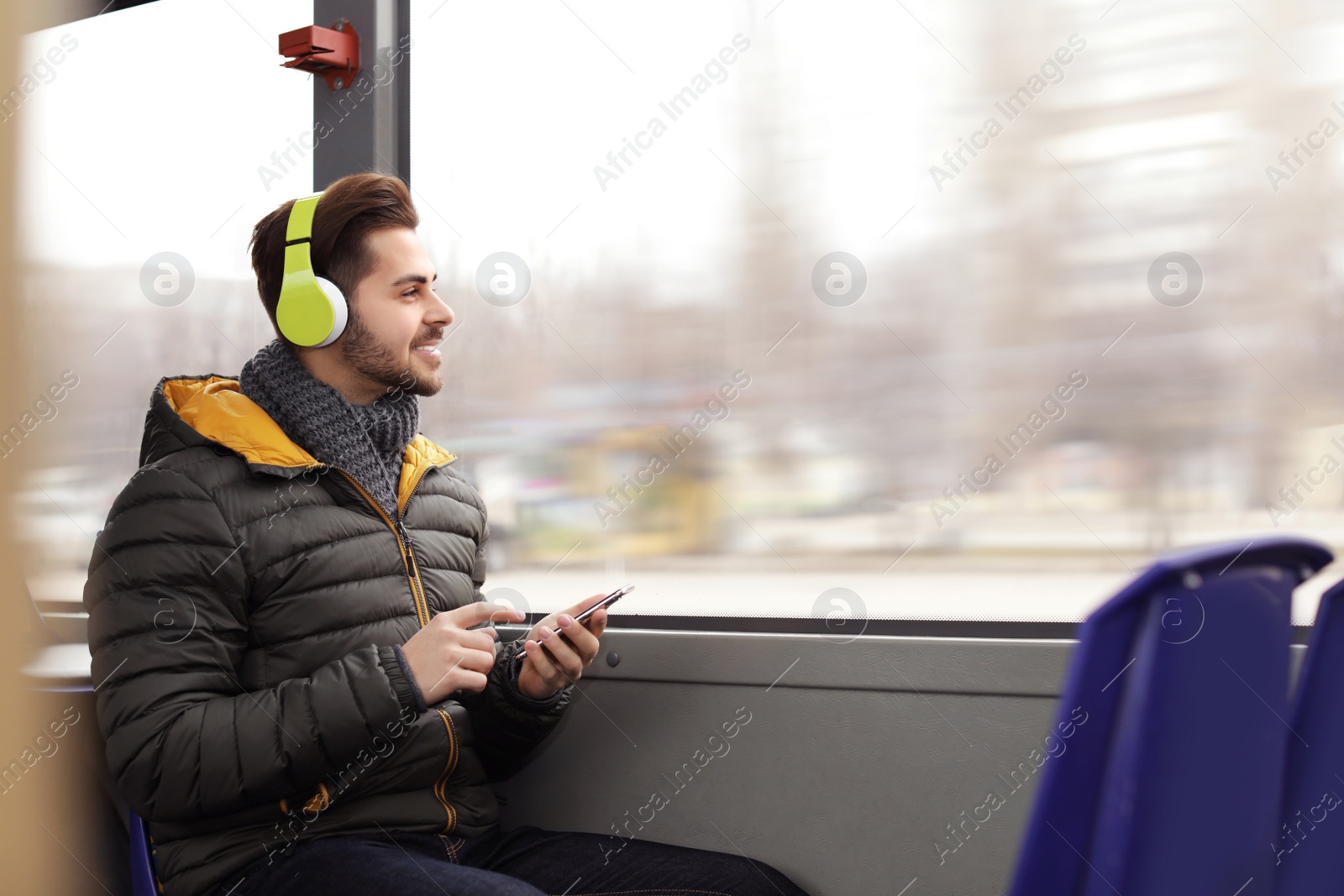 Photo of Young man listening to music with headphones in public transport