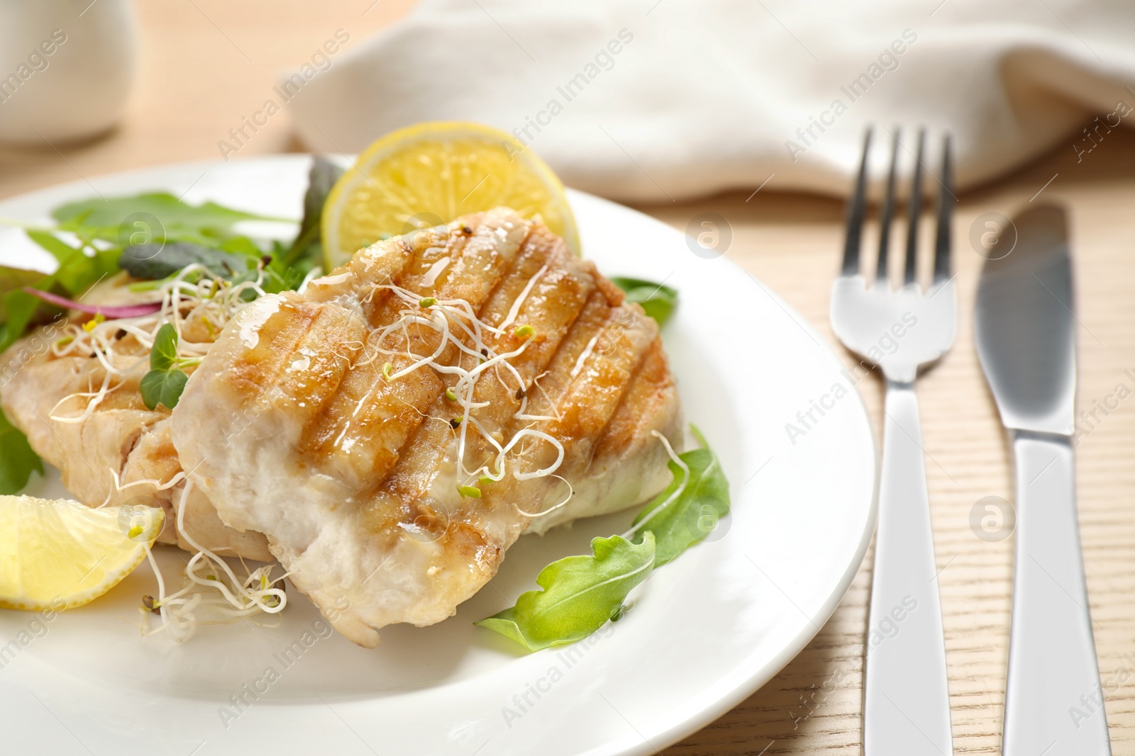 Photo of Tasty grilled fish served on wooden table, closeup