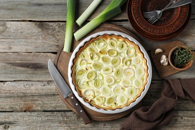 Photo of Tasty leek pie, knife and products on old wooden table, flat lay. Space for text
