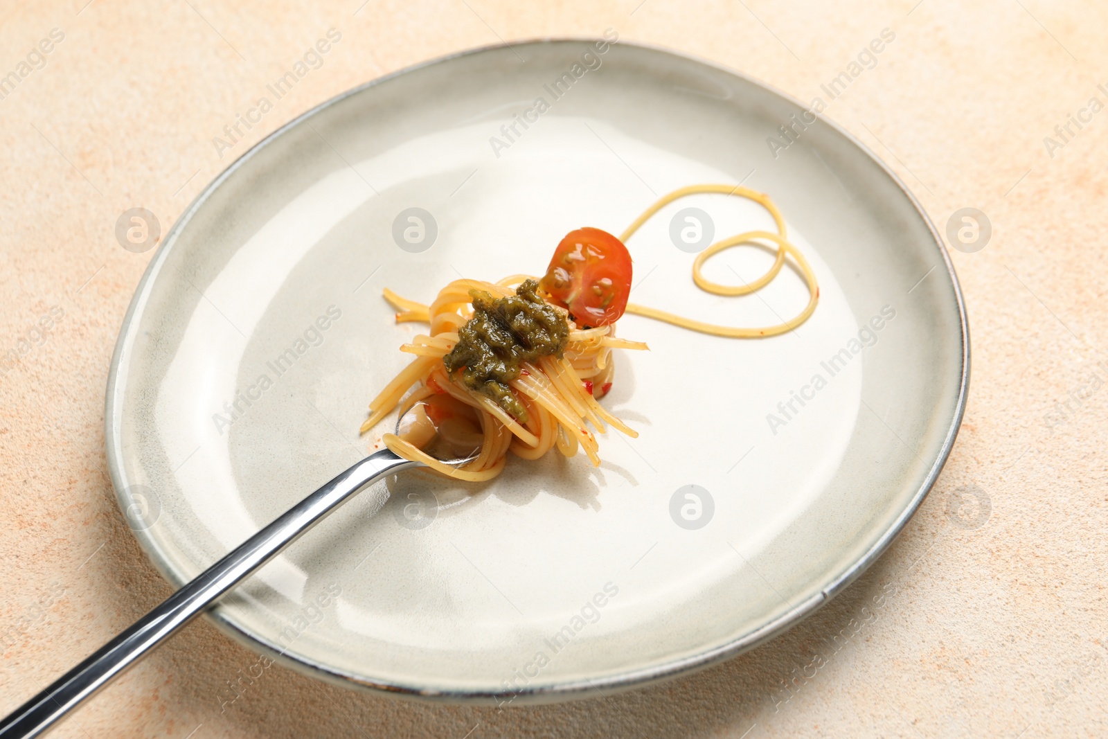 Photo of Heart made with spaghetti and fork on beige table