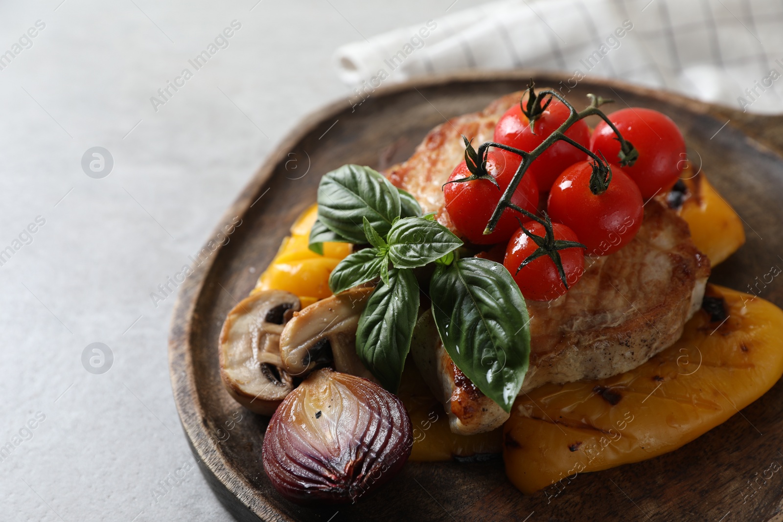 Photo of Serving board with tasty grilled meat and vegetables on light table, closeup