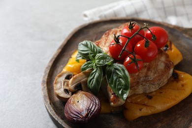 Serving board with tasty grilled meat and vegetables on light table, closeup