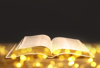 Image of Open Bible on wooden table, bokeh effect