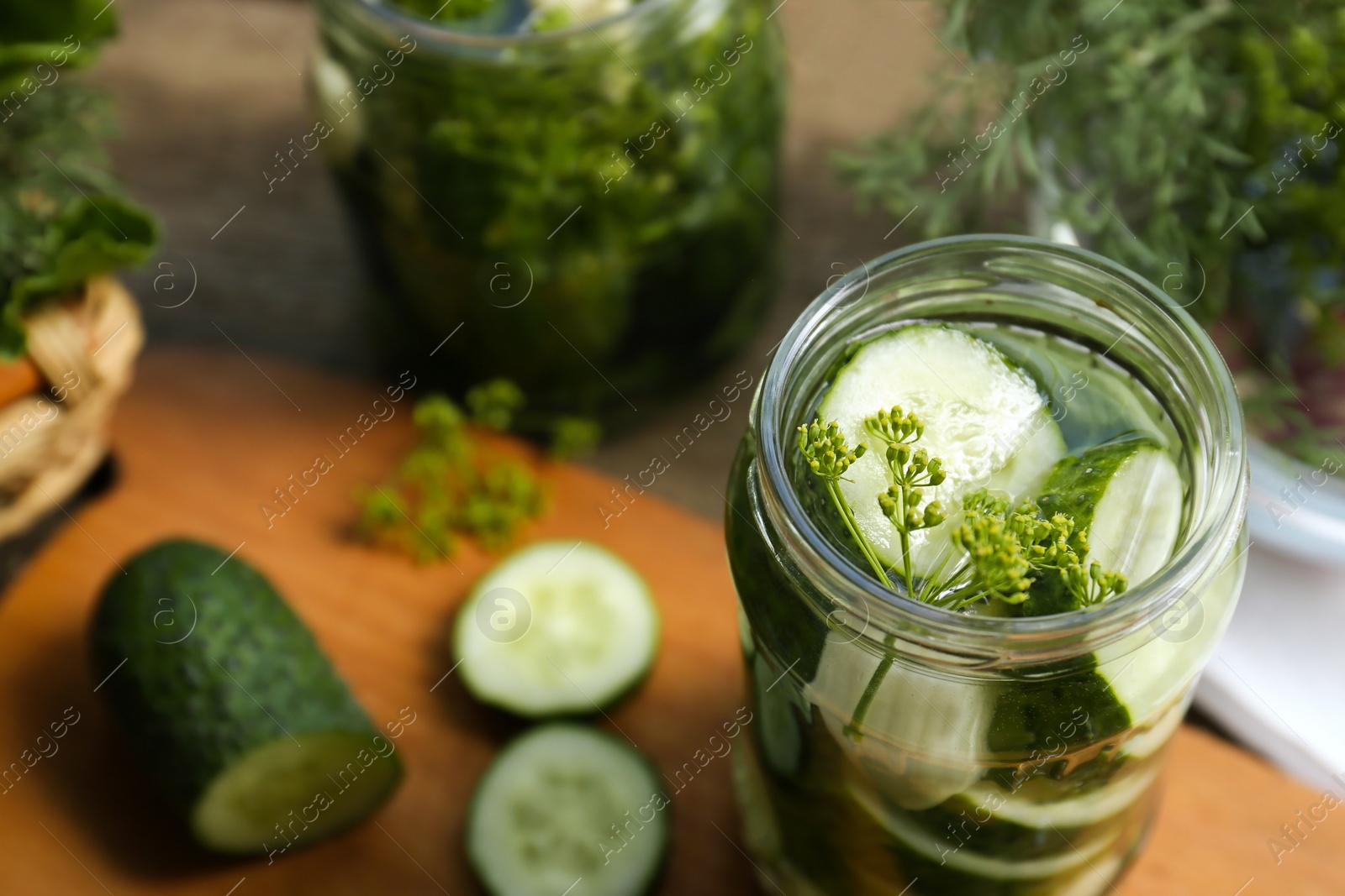 Photo of Glass jar with cucumber slices, dill and brine on table, closeup. Pickling recipe