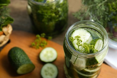 Glass jar with cucumber slices, dill and brine on table, closeup. Pickling recipe